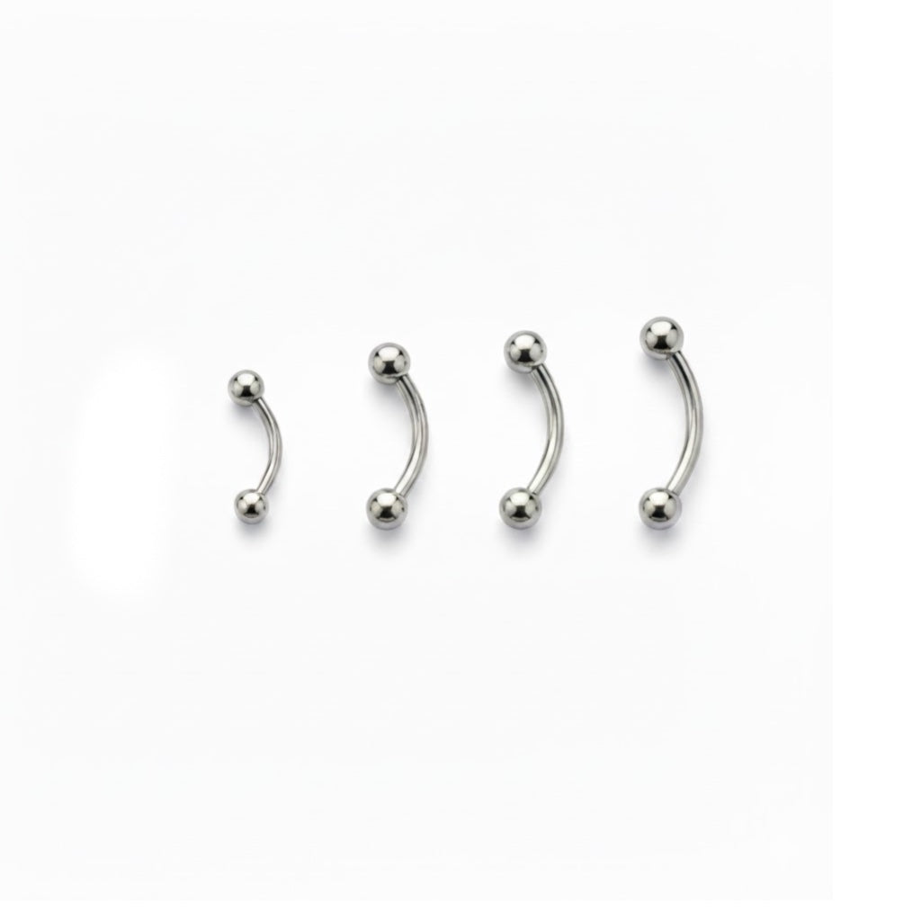 Piercing a bananina (curved barbell) in titanio di grado implantare, con palline a vite. Barra curva ipoallergenica per piercing all'ombelico, sopracciglio o rook. Disponibile in diverse lunghezze.