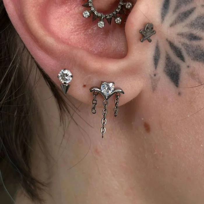 Gioiello pendente "Bling Triple Chain" in titanio di grado implantare, composto da tre catenelle sottili che creano un effetto cascata. Dettagli brillanti o con micro-cristalli. Perfetto per helix o lobo per un look a strati.