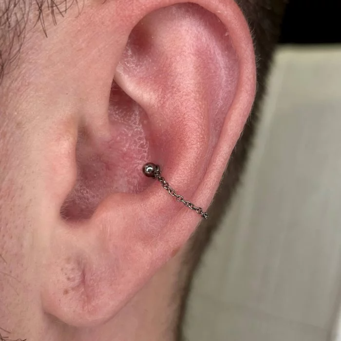 Catenella pendente "Chain" in titanio di grado implantare, utilizzata come decorazione su un singolo piercing al Conch (conch chain). Collega due punti della stessa barretta/labret. Accessorio ipoallergenico e personalizzabile