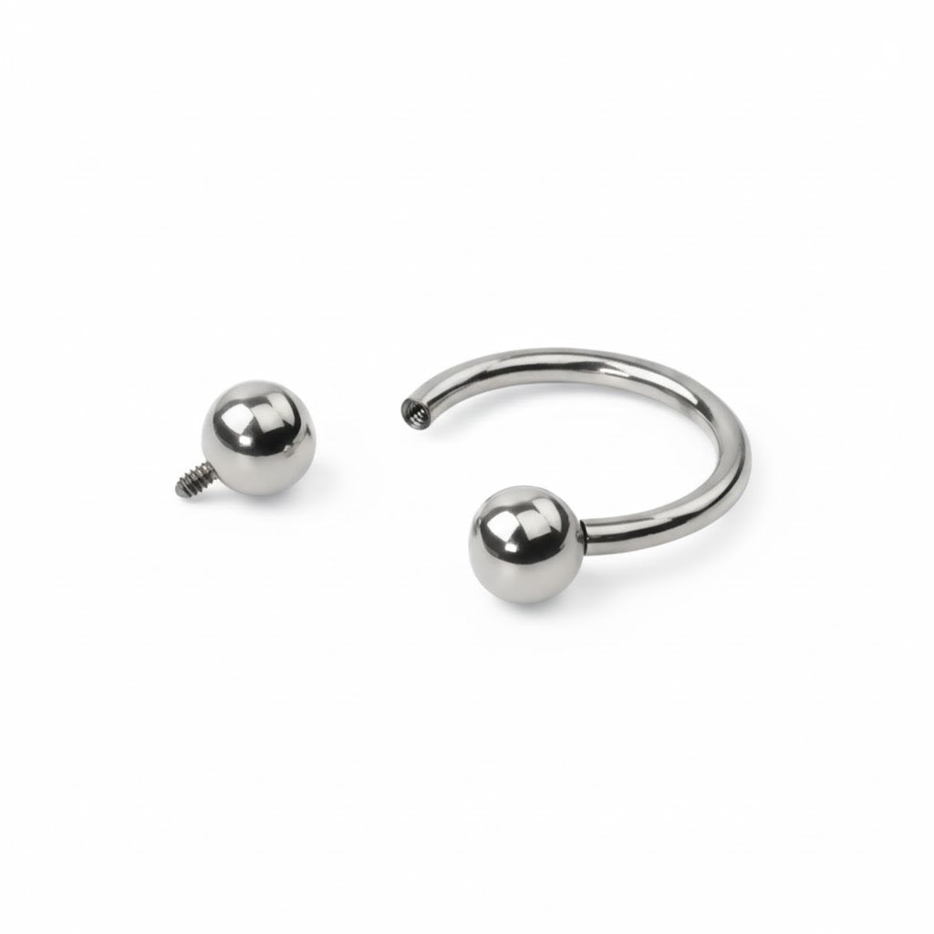 Piercing a ferro di cavallo (circular barbell) in titanio di grado implantare, con palline a vite. Anello base ipoallergeni. Disponibile in diverse misure.
