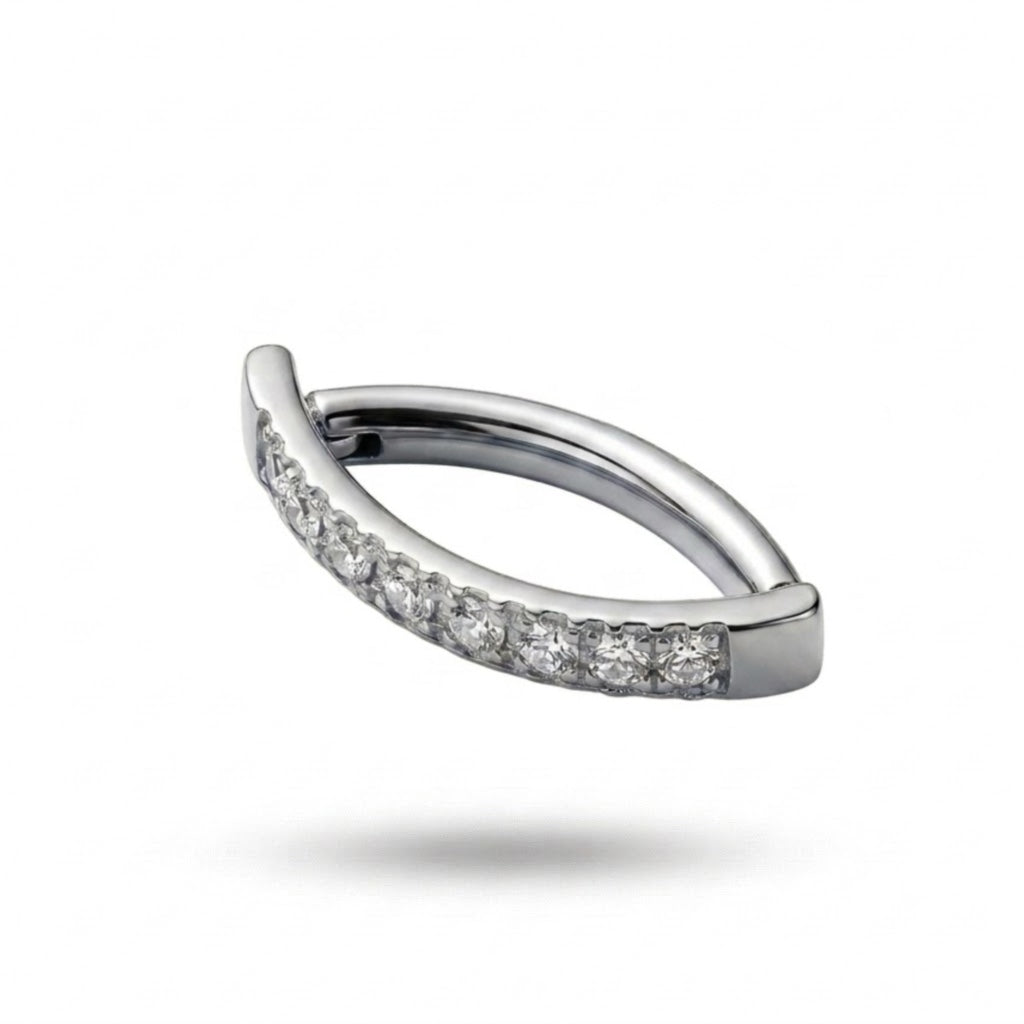 Piercing da ombelico ad anello realizzato in Titanio ASTM F136, con una raffinata fila di cristalli luminosi che dona brillantezza e un tocco elegante al gioiello. Il design è perfetto per chi cerca un piercing ombelico in titanio che unisca comfort, semplicità e luminosità.