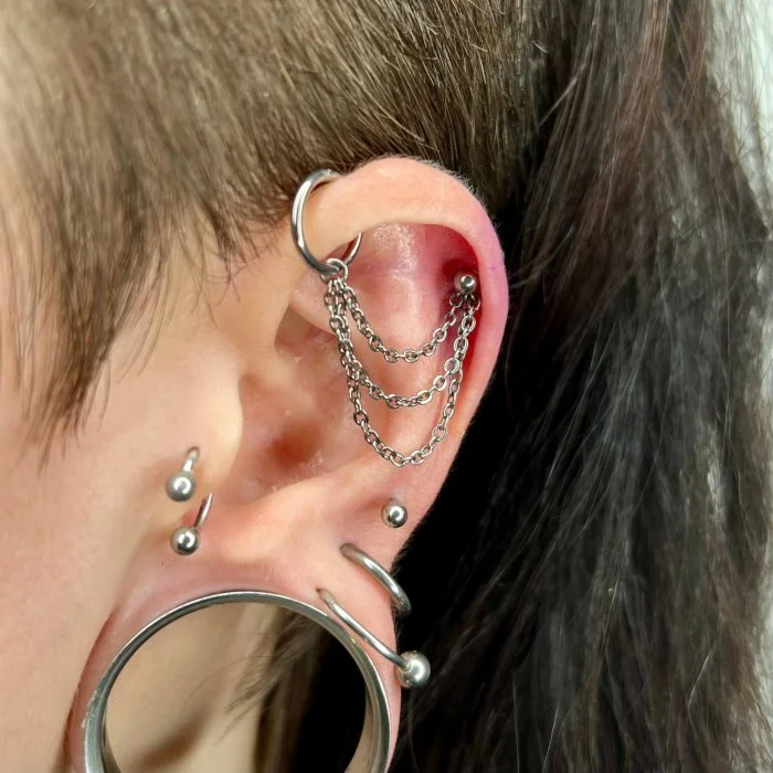 Catenella tripla "Triple Chain" in titanio di grado implantare. Accessorio per collegare due fori (piercing Helix e Forward Helix), creando un look a strati di gioielli. Ipoallergenico e professionale.