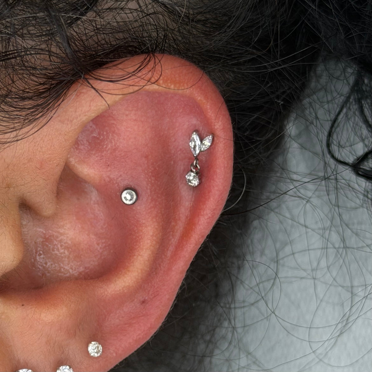 Elegante e luminoso, questo gioiello per piercing in titanio certificato è caratterizzato da un design ricco di dettagli e da un raffinato pendente con zircone che dona movimento e brillantezza al gioiello.
