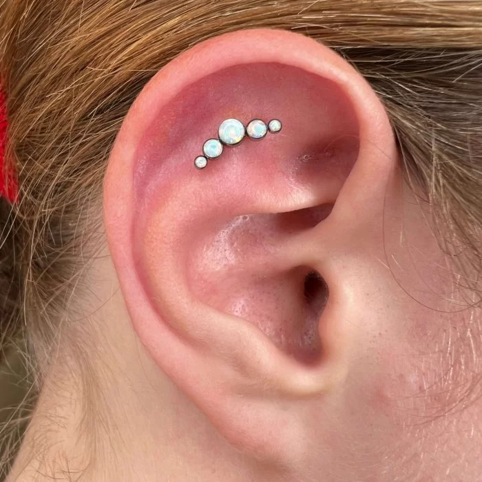 Gioiello piercing Cluster Opale a Cinque Elementi in Titanio Chirurgico indossato. Design anallergico con cinque opali scintillanti, perfetto per aggiungere luce a helix, conch o flat.