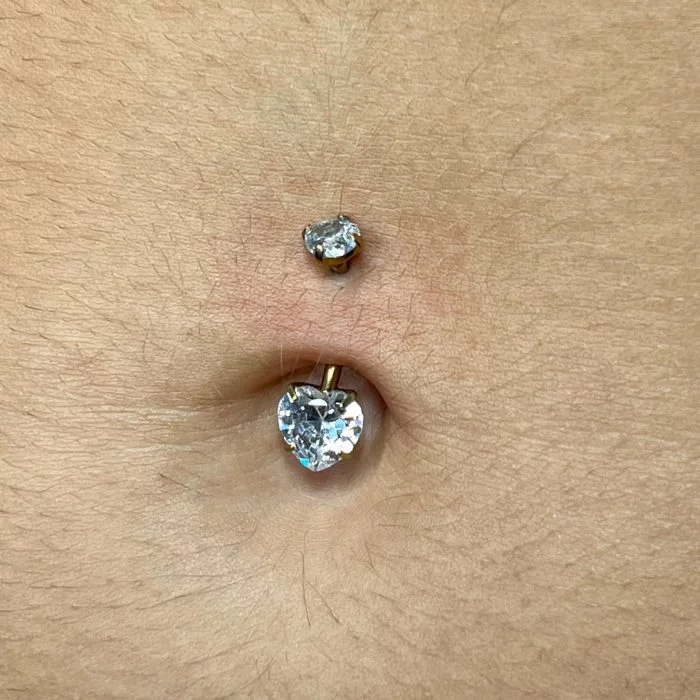 Il suo design a cuore aggiunge un tocco romantico e femminile all’ombelico, valorizzando ogni movimento con una luce discreta e raffinata. Grazie al titanio, questo piercing è leggero, resistente e durevole, garantendo massima comodità anche durante l’uso quotidiano.