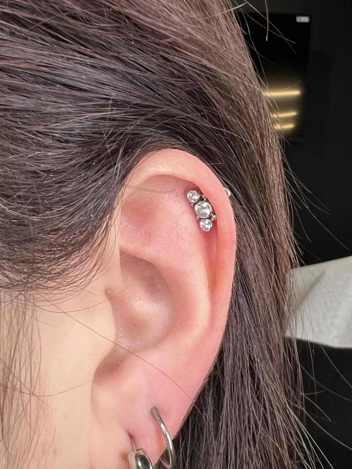 Dettaglio di una composizione piercing con Little Cluster sobrio ed elegante, montato su orecchio. Materiale: Titanio.