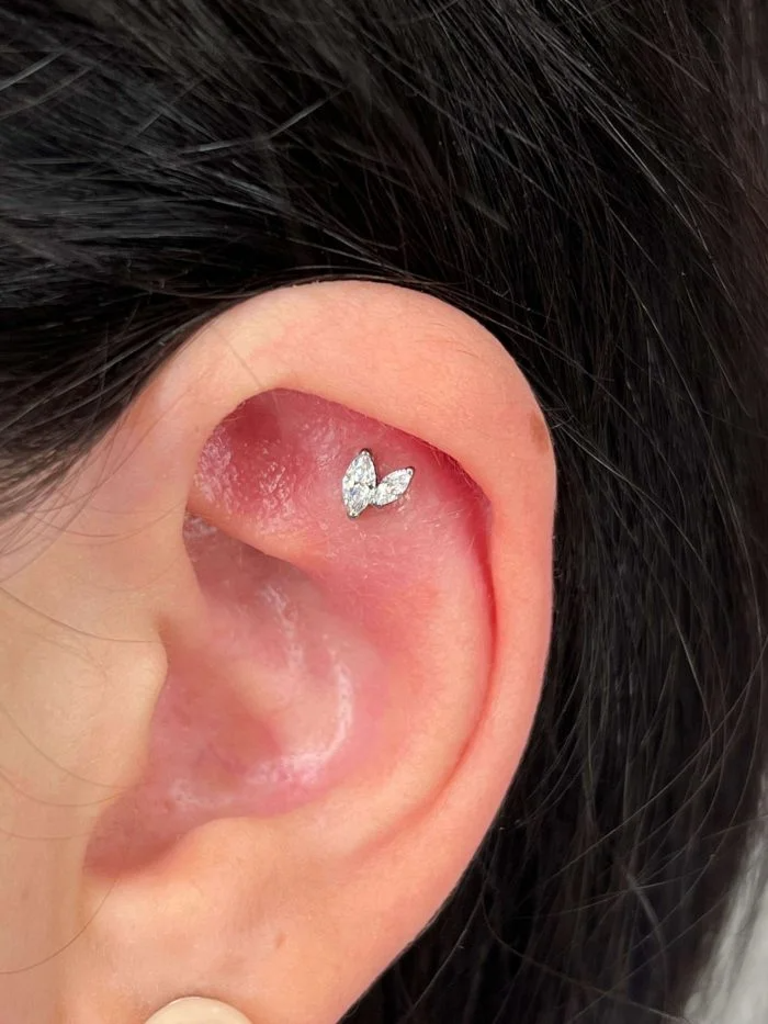 Piercing in titanio ipoallergenico con design minimal a V e cristallo marquise brillante.
