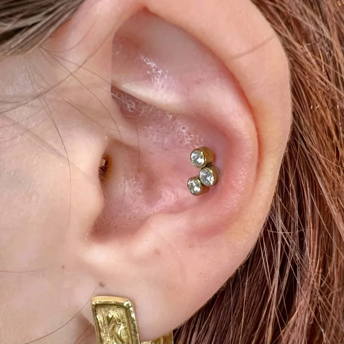 Piercing in titanio ipoallergenico con tre micro cristalli a cluster, ideale per look discreti e luminosi.