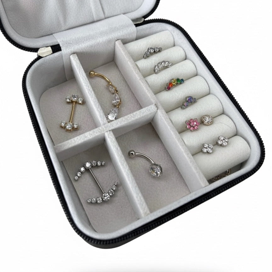 Porta gioielli Noa Ink Case nero opaco aperto, con orecchini e piercing all’interno. Design minimal e compatto con logo Noa Ink inciso, ideale per conservare e presentare gioielli in modo ordinato ed elegante.