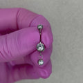 Piercing da ombelico in Titanio ASTM F136 dal design elegante e luminoso. La pietra centrale è arricchita da un delicato pendente con cristallo, creando un effetto raffinato e leggermente movimento sul piercing.
Perfetto per chi cerca un navel piercing con pendente elegante e versatile, capace di aggiungere un piccolo punto luce senza risultare eccessivo.