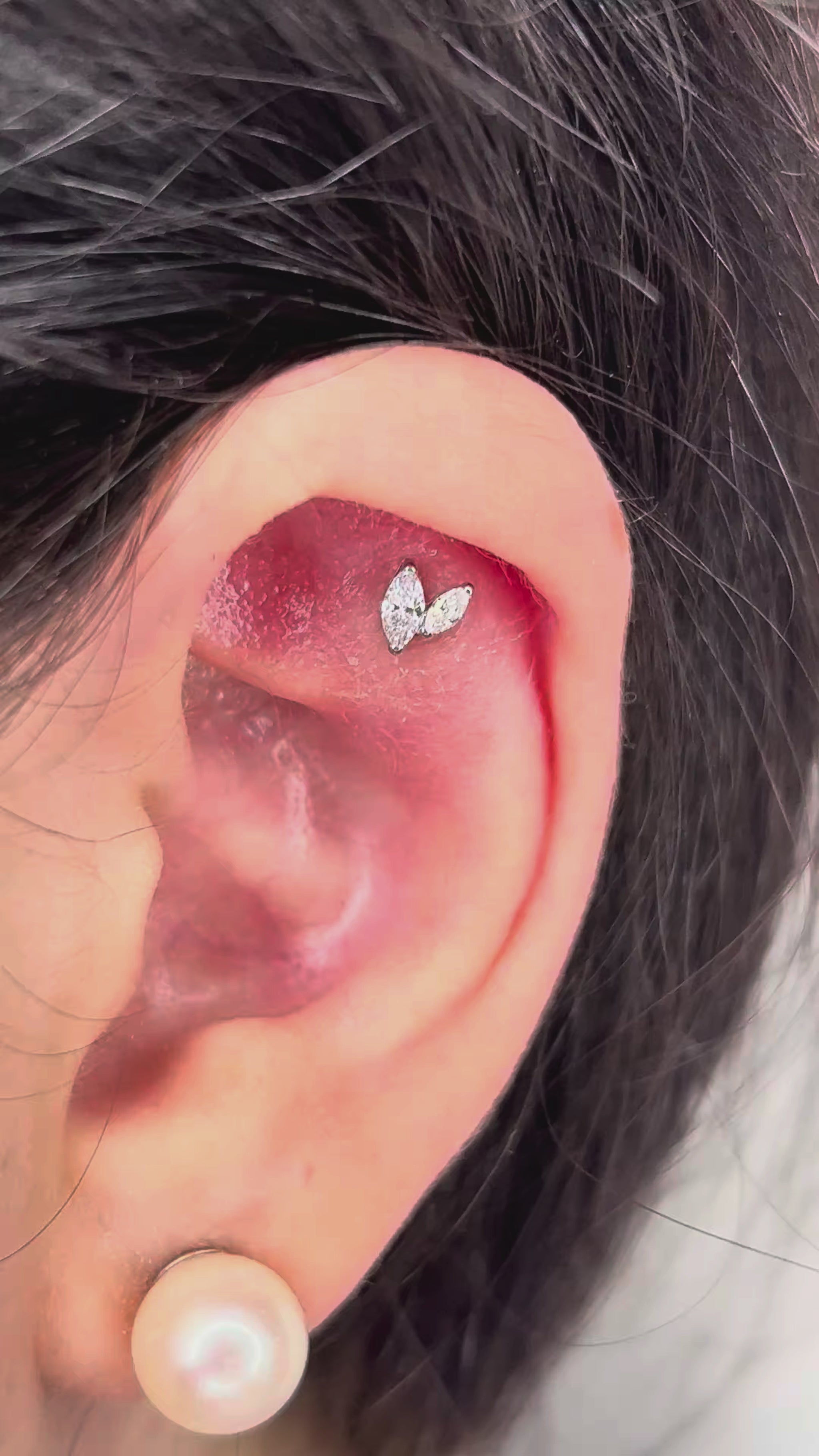 Piercing in titanio ipoallergenico con design minimal a V e cristallo marquise brillante.