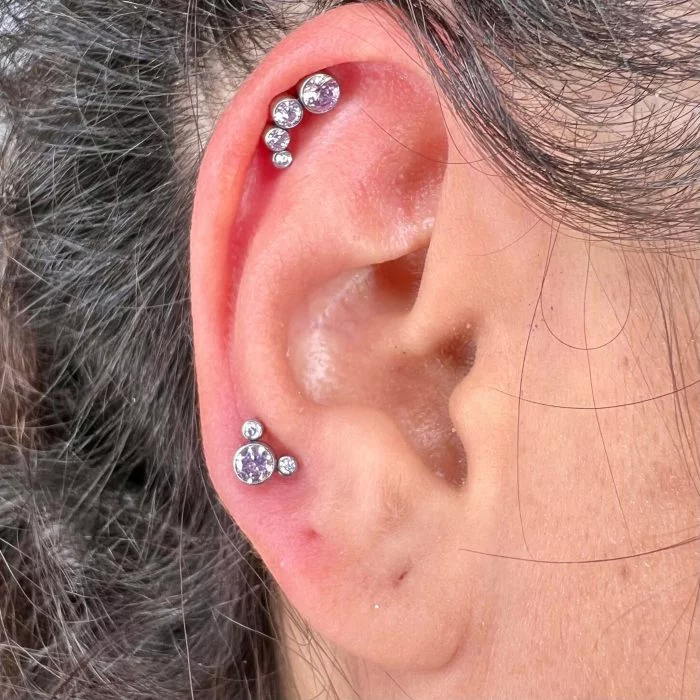 Piercing indossato Cluster Quadruplo realizzato in Titanio Chirurgico. Quattro cristalli di zircone raggruppati, massima brillantezza, ideale per trago, helix o lobo alto.